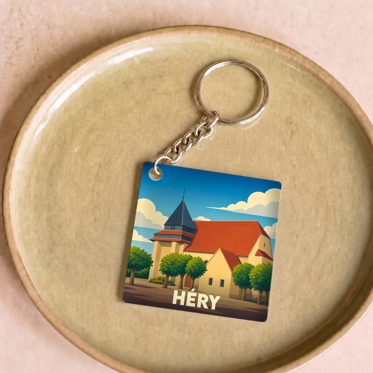 Porte-clés souvenir de la ville de Héry avec une illustration stylisée de son église.