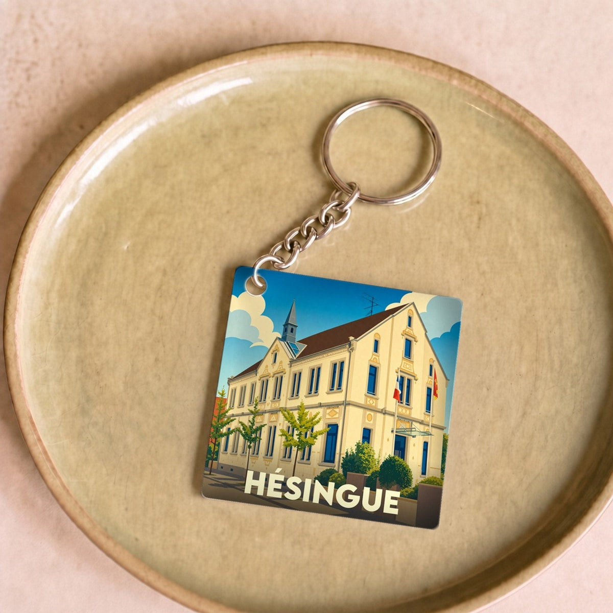 Porte-clés souvenir de la ville de Hésingue avec une illustration stylisée.