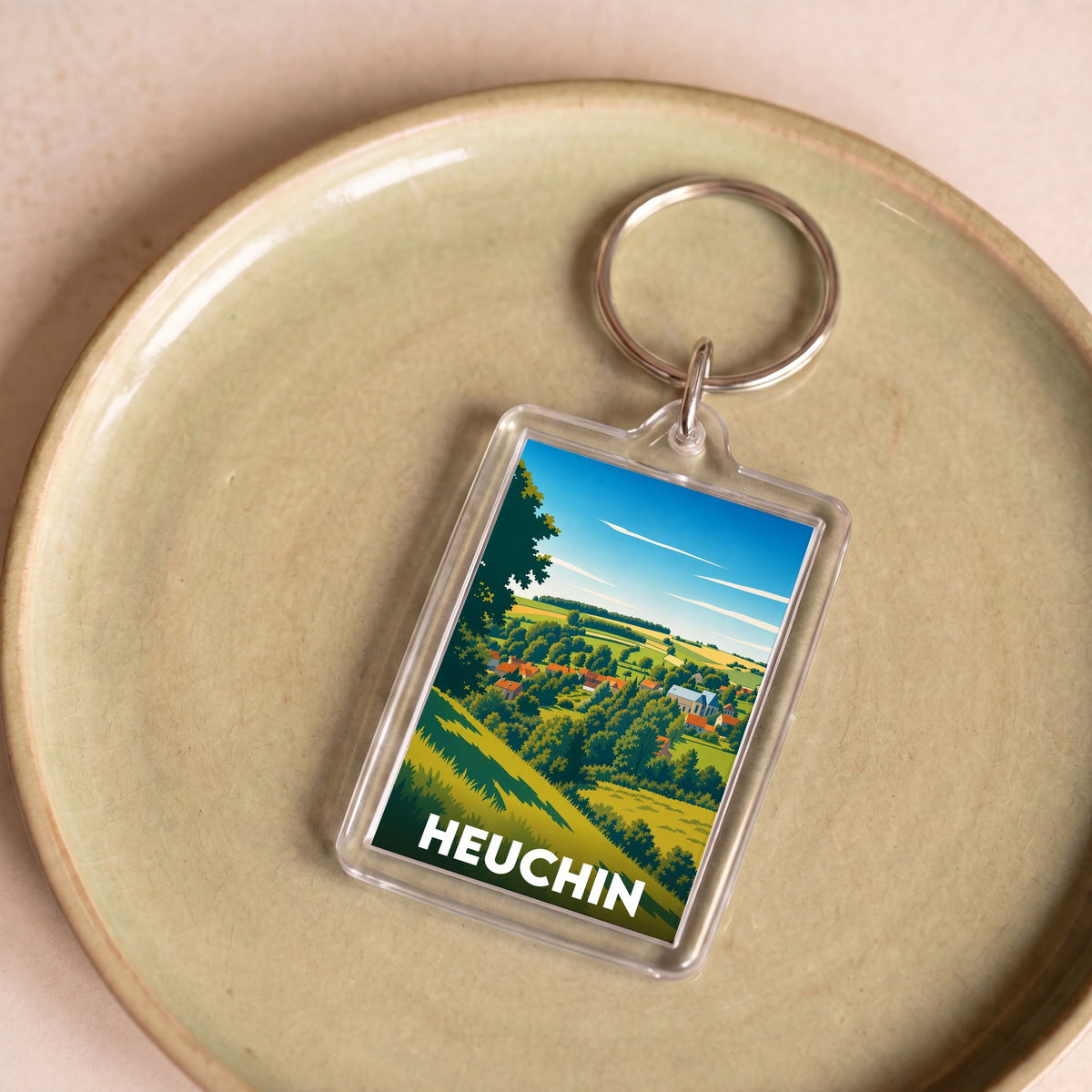 Porte-clés souvenir de la ville de Heuchin avec une illustration stylisée.
