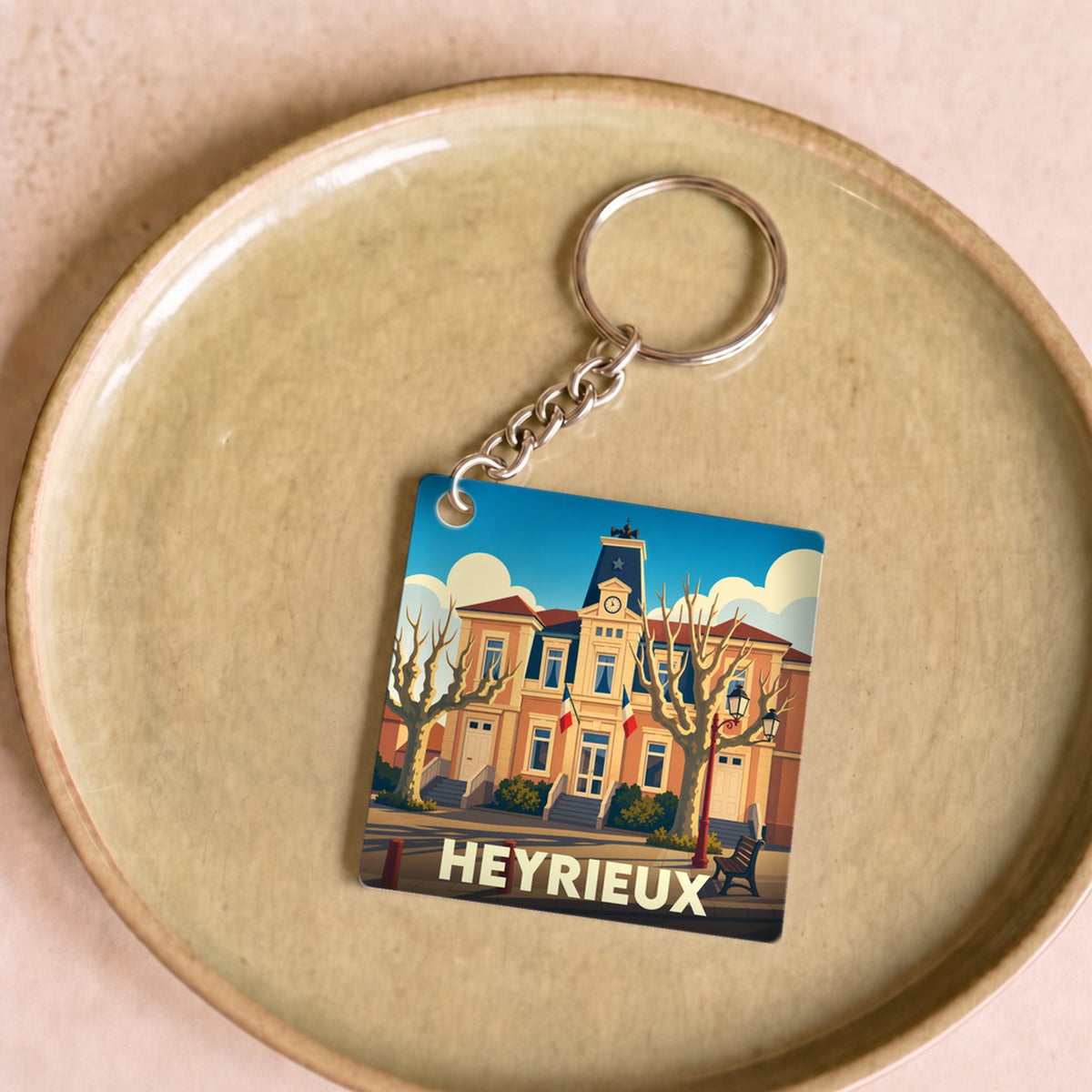 Porte-clés souvenir de la ville de Heyrieux avec une illustration stylisée de son hôtel de ville.