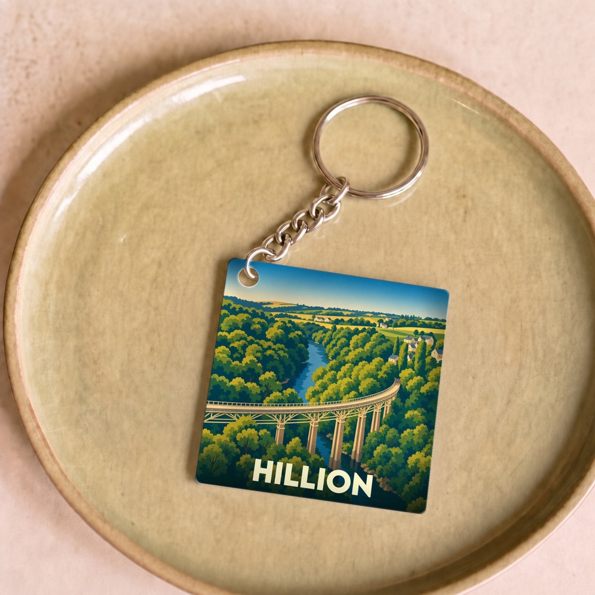 Porte-clés souvenir de la ville de Hillion avec une illustration stylisée d'un viaduc surplombant une vallée verdoyante.