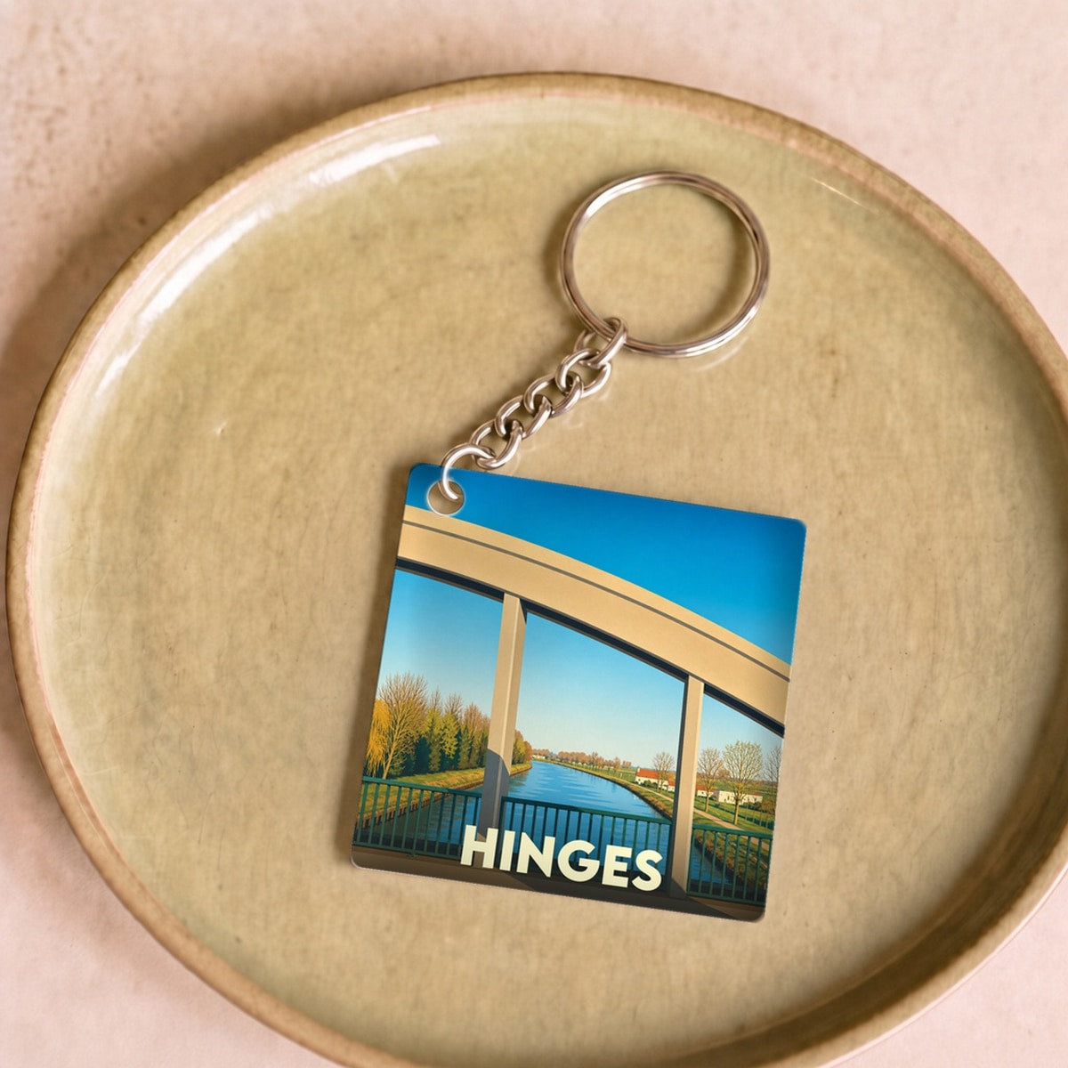 Porte-clés souvenir de la ville de Hinges avec une illustration stylisée de son pont au-dessus du canal.