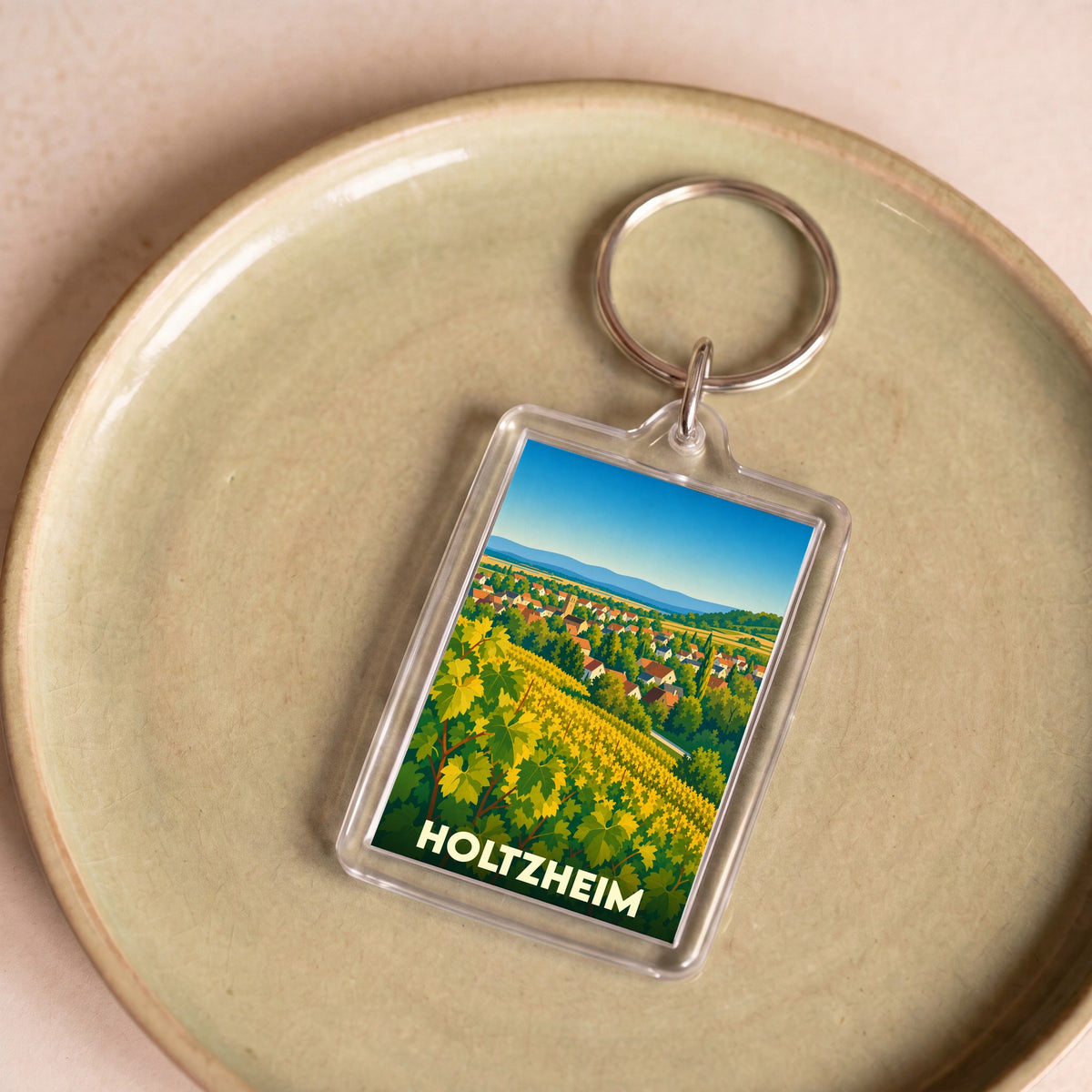 Porte-clés souvenir de la ville de Holtzheim avec une illustration stylisée de vignobles et du village.