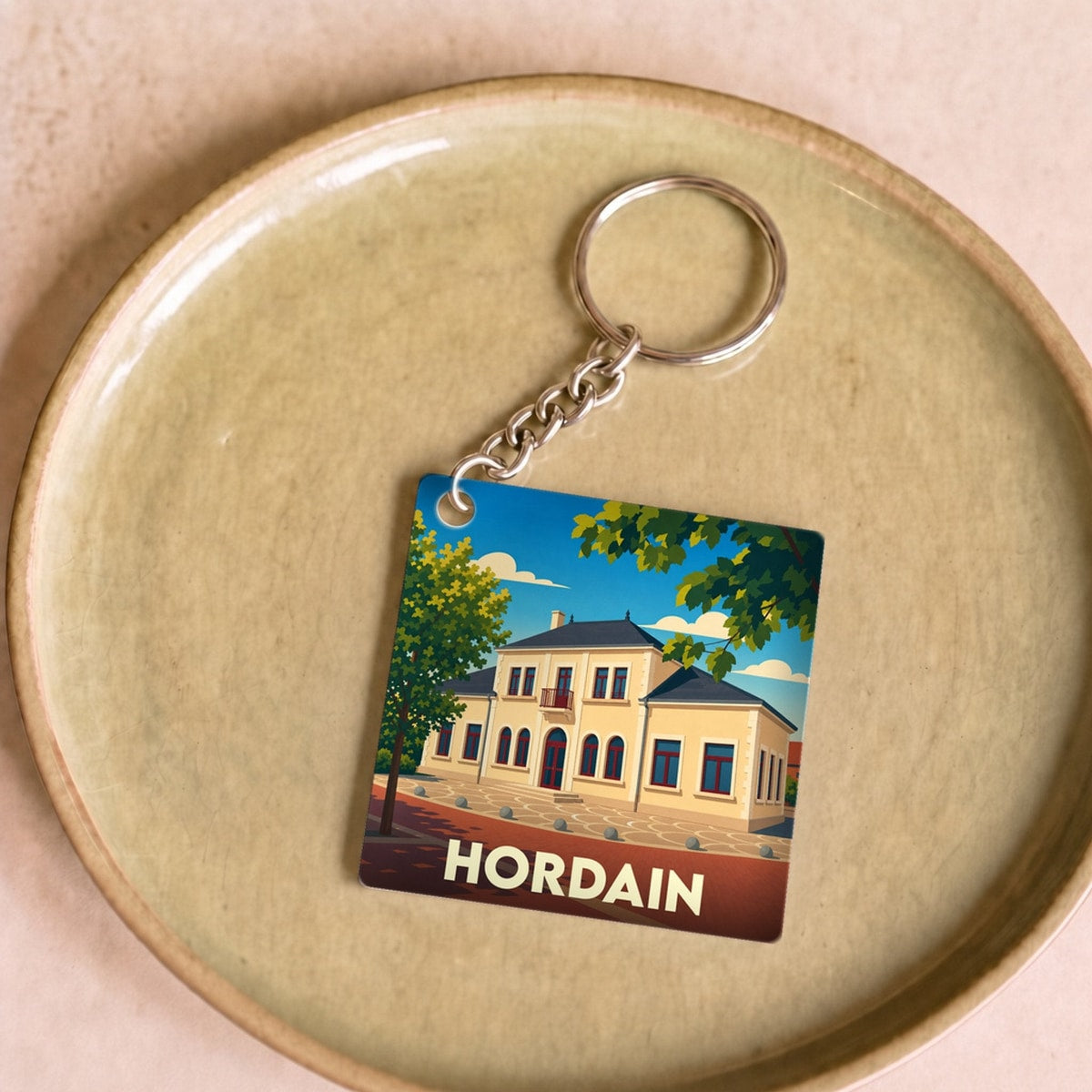 Porte-clés souvenir de la ville de Hordain avec une illustration stylisée d'un bâtiment emblématique.