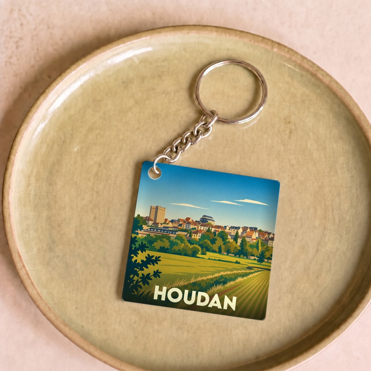 Porte-clés souvenir de la ville de Houdan avec une illustration stylisée de son paysage et de son donjon.