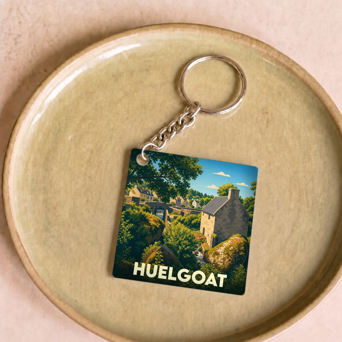 Porte-clés souvenir de la ville de Huelgoat avec une illustration stylisée d'un paysage breton.