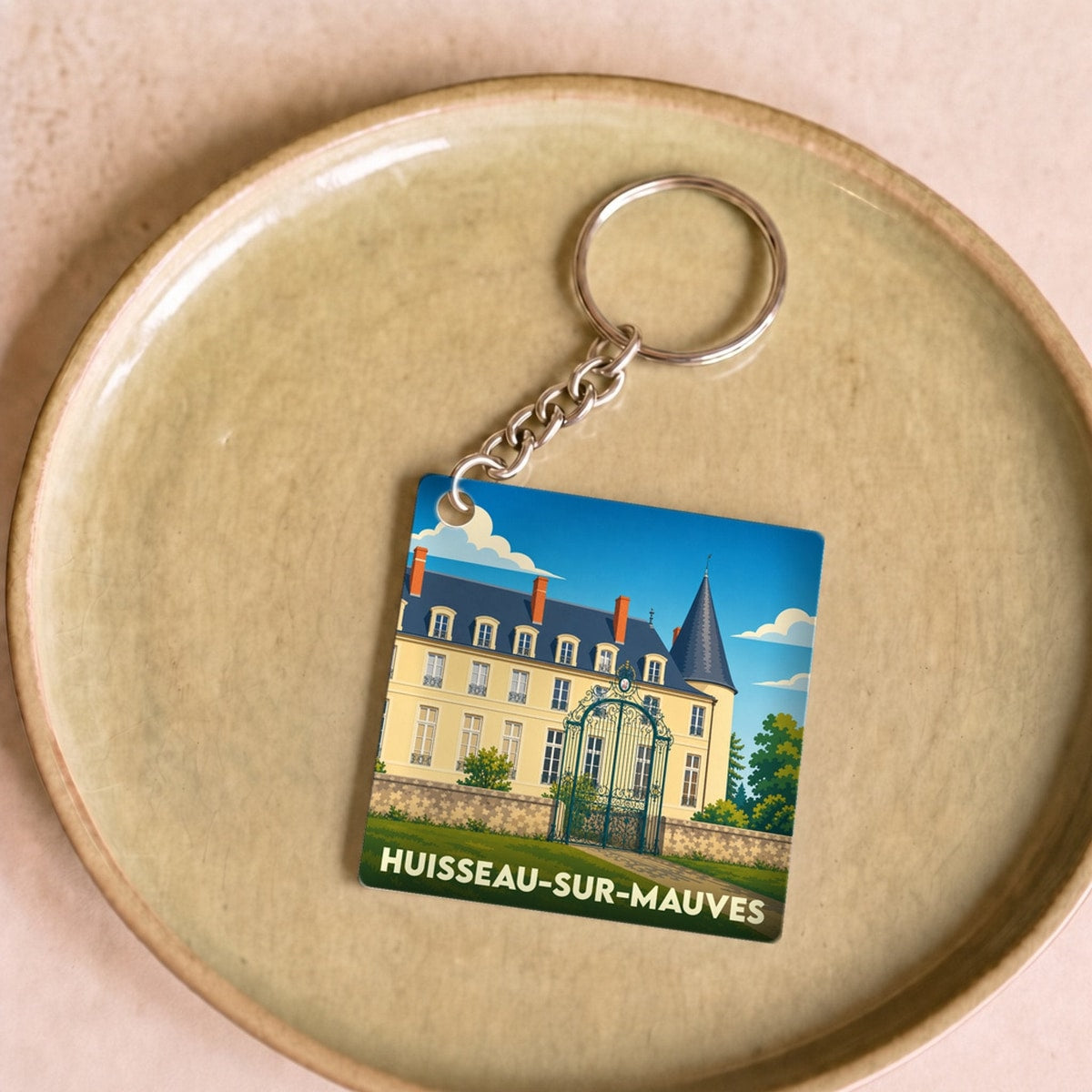 Porte-clés souvenir de la ville de Huisseau-sur-Mauves avec une illustration stylisée d'un château.