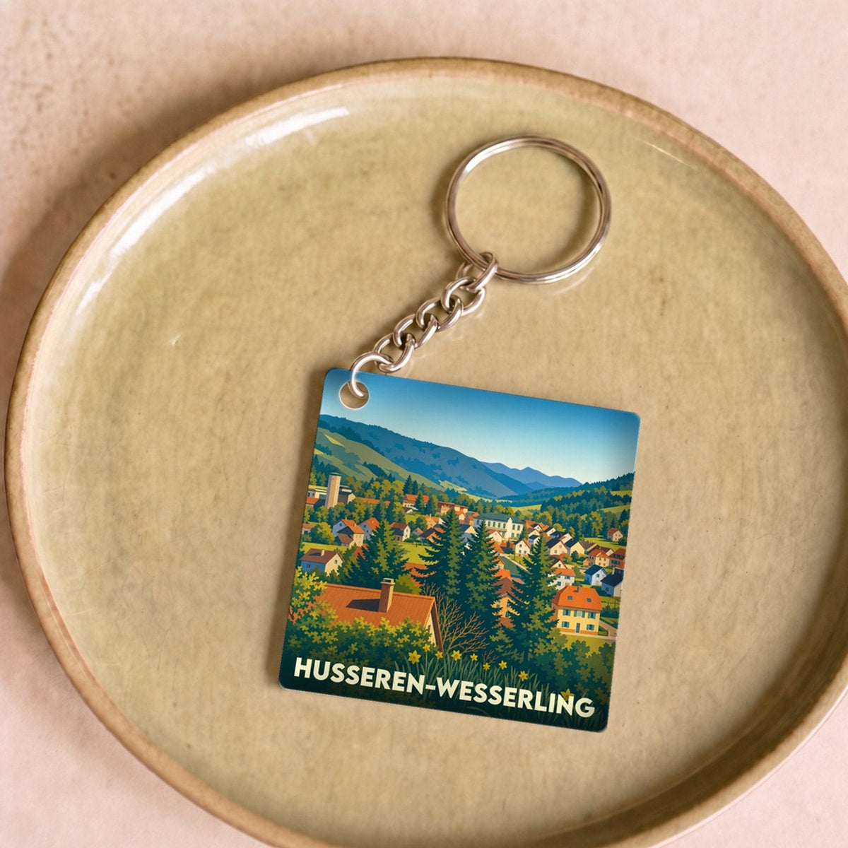 Porte-clés souvenir de la ville de Husseren-Wesserling avec une illustration stylisée d'un paysage montagneux.