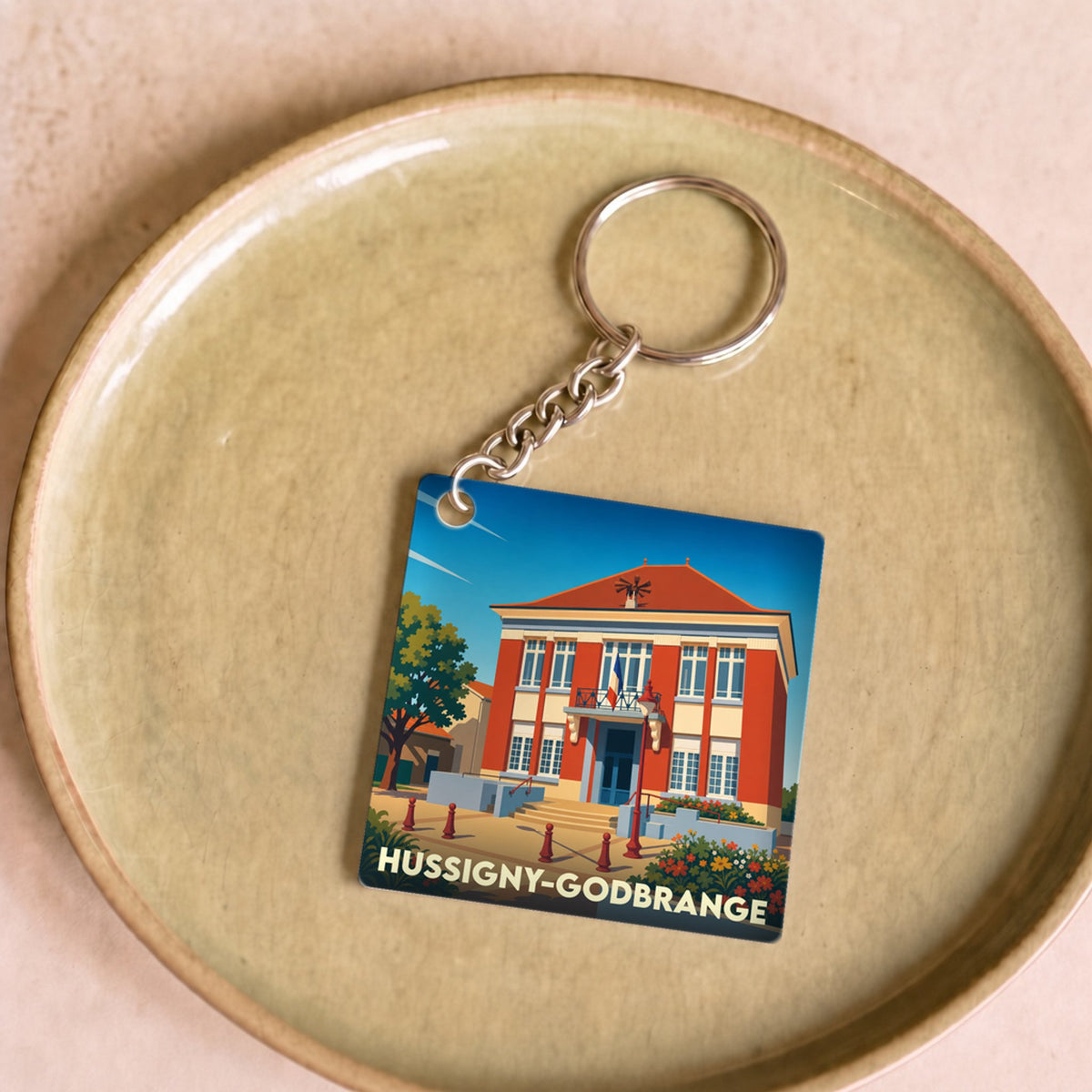 Porte-clés souvenir de la ville de Hussigny-Godbrange avec une illustration stylisée de sa mairie.