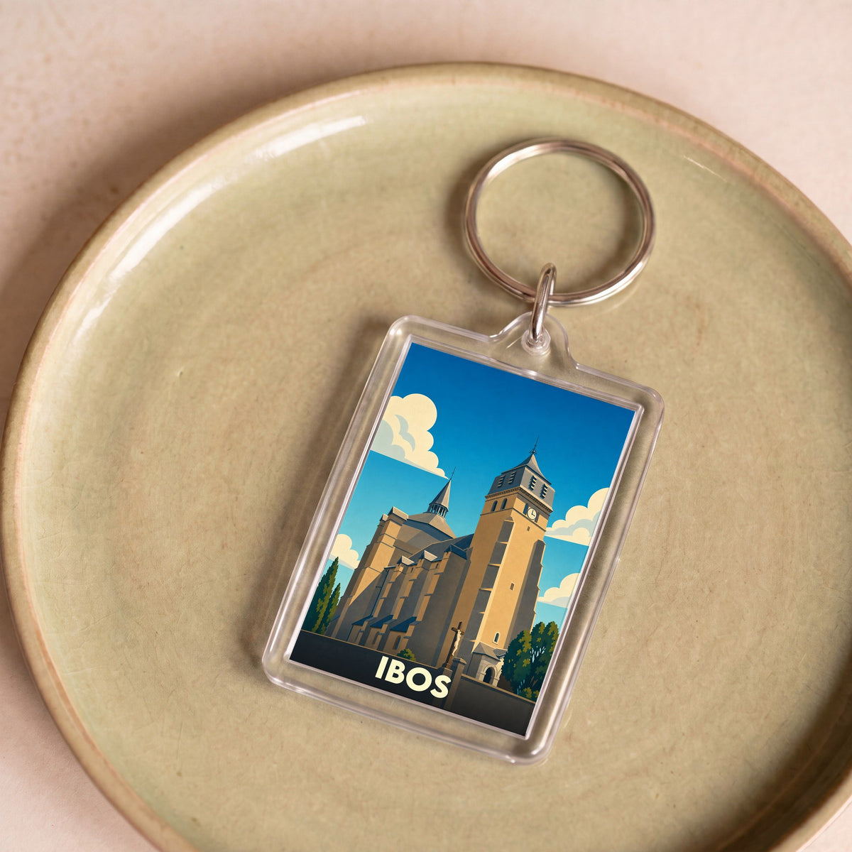 Porte-clés souvenir de la ville d'Ibos avec une illustration stylisée de son église collégiale.