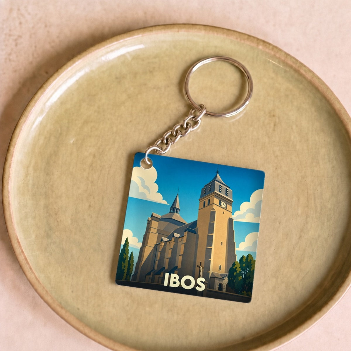 Porte-clés souvenir de la ville d'Ibos avec une illustration stylisée de son église collégiale.