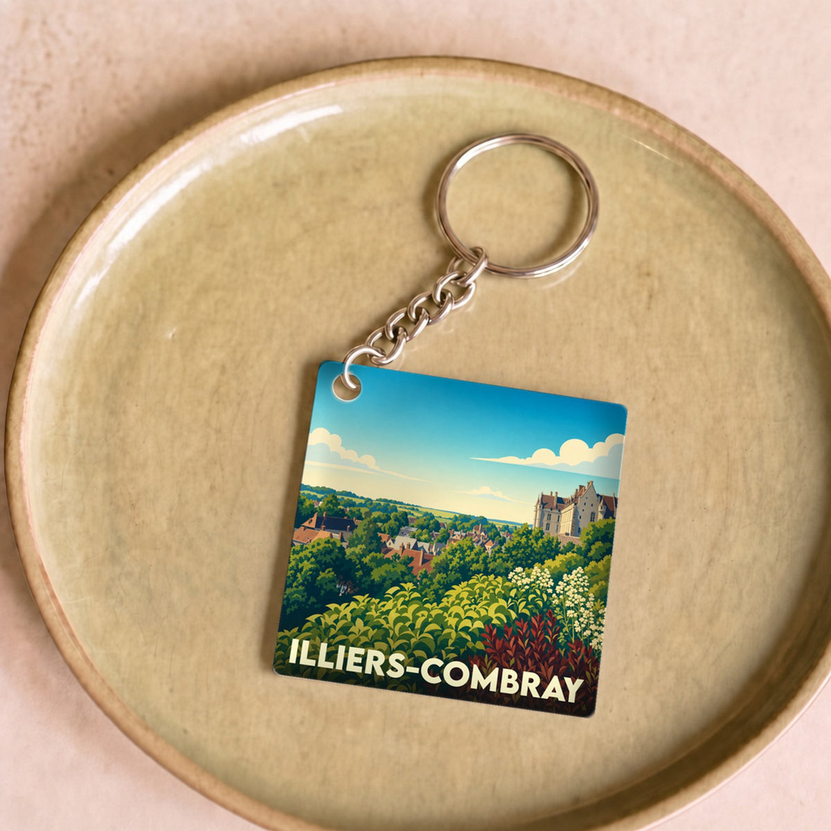Porte-clés souvenir de la ville de Illiers-Combray avec une illustration paysagère stylisée.
