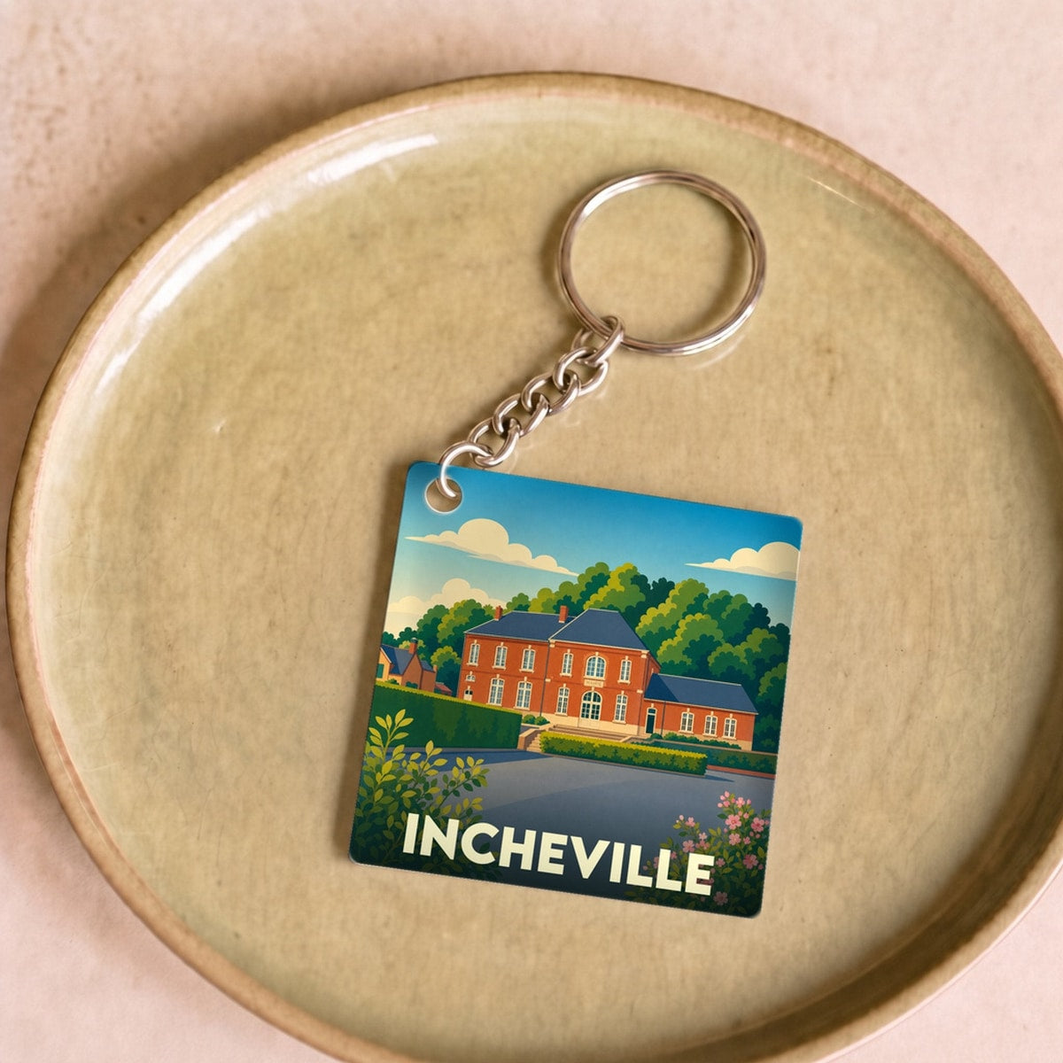 Porte-clés souvenir de la ville d'Incheville avec une illustration stylisée.