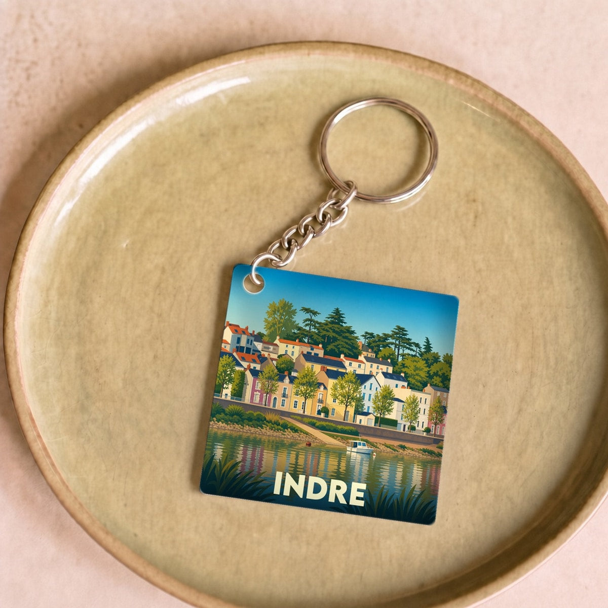 Porte-clés souvenir de la ville d'Indre avec une illustration stylisée d'un paysage fluvial.