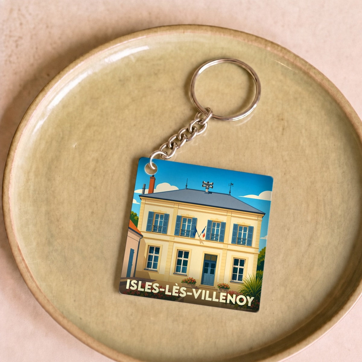 Porte-clés souvenir de la ville de Isles-lès-Villenoy avec une illustration stylisée de la mairie.