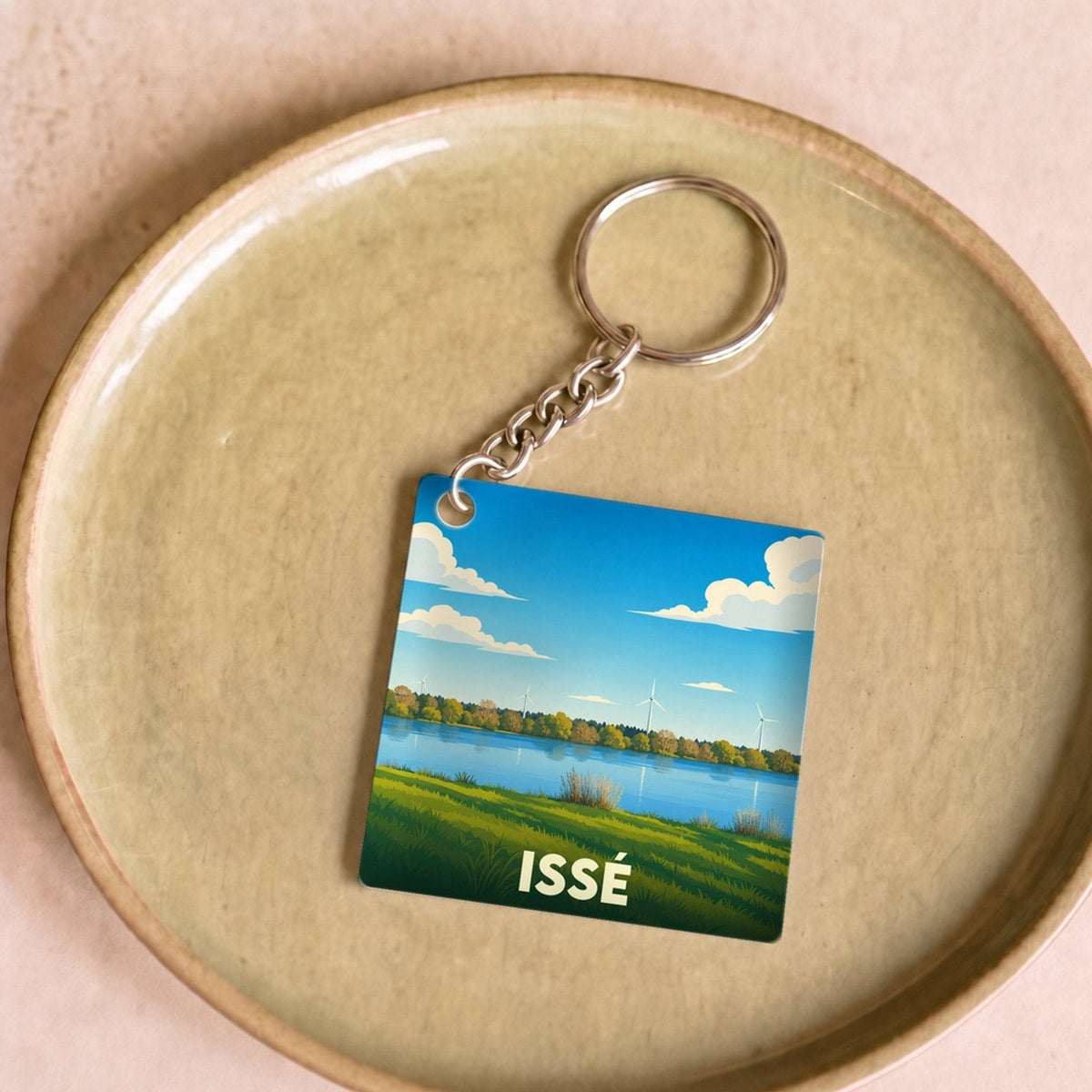 Porte-clés souvenir de la ville de Issé avec une illustration stylisée de son paysage.