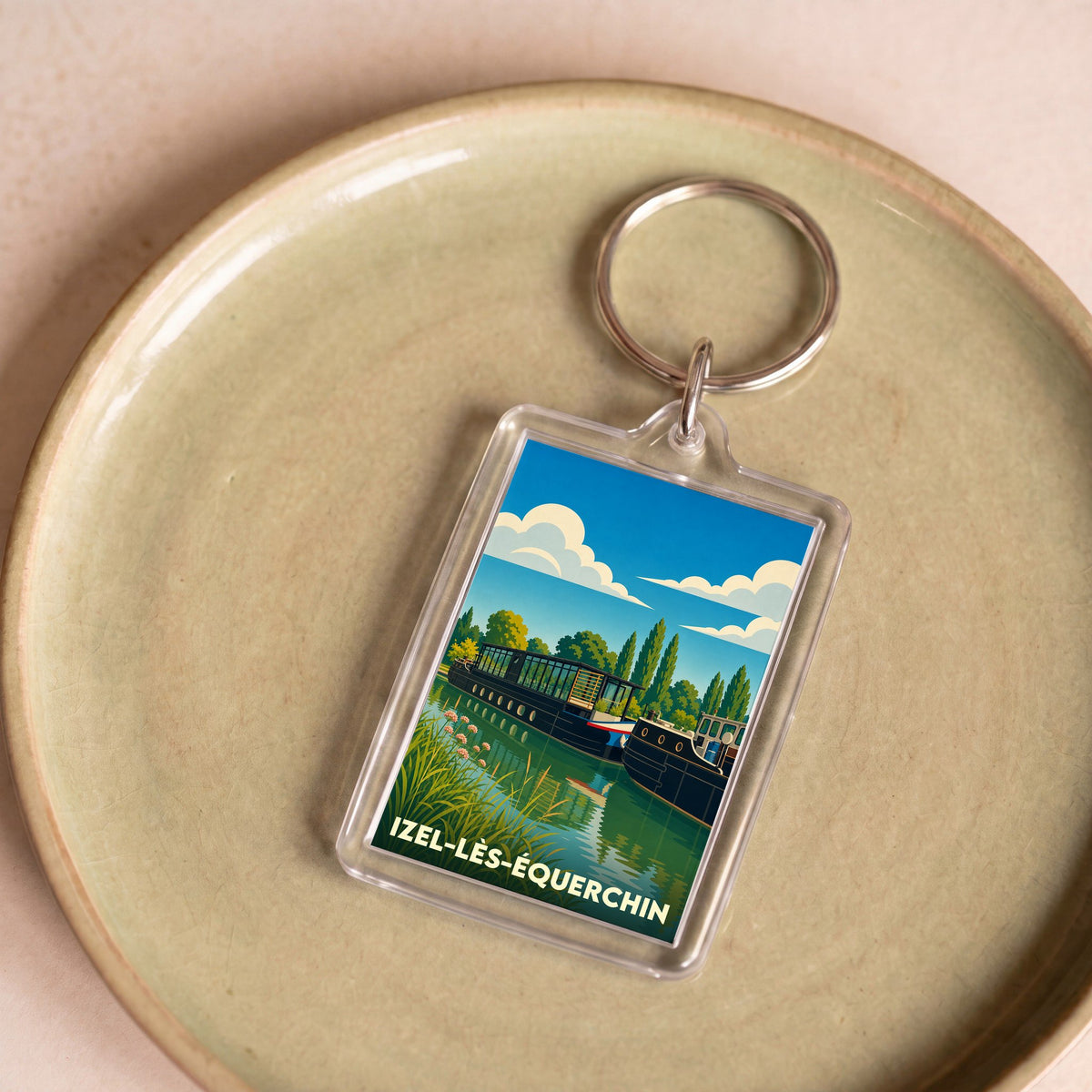 Porte-clés souvenir de la ville de Izel-lès-Équerchin avec une illustration stylisée de péniches sur l'eau.