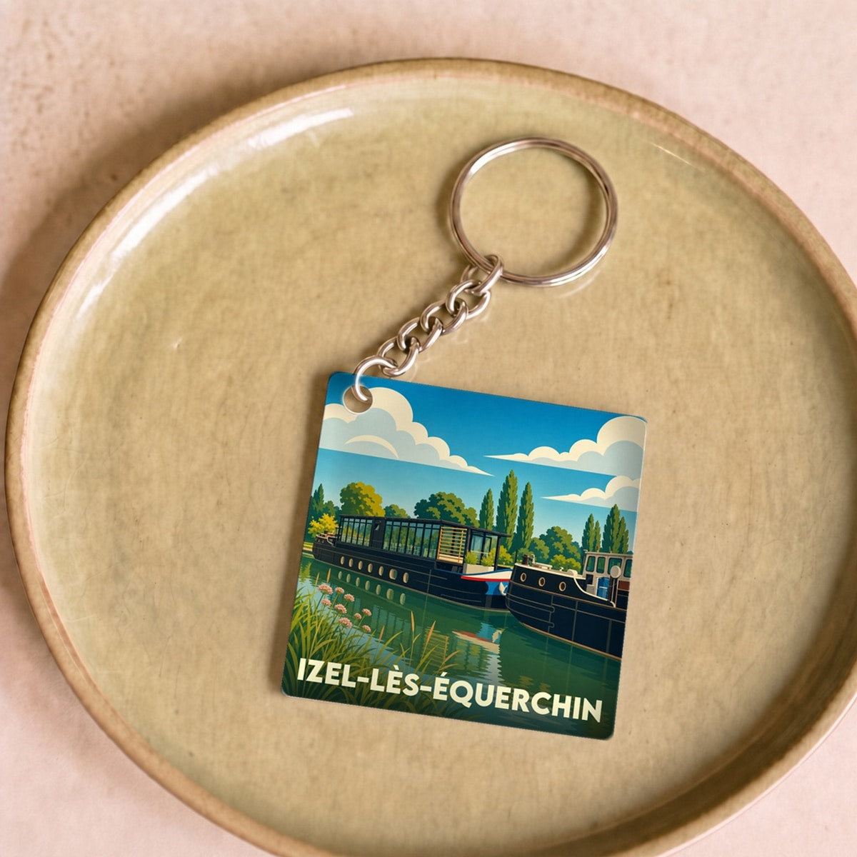 Porte-clés souvenir de la ville de Izel-lès-Équerchin avec une illustration stylisée de péniches sur l'eau.