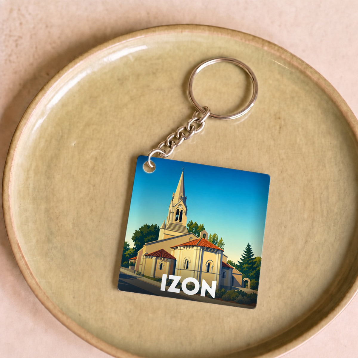 Porte-clés souvenir de la ville d'Izon avec une illustration stylisée de son église.