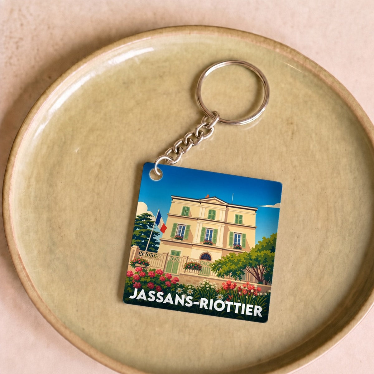 Porte-clés souvenir de la ville de Jassans-Riottier avec une illustration stylisée.