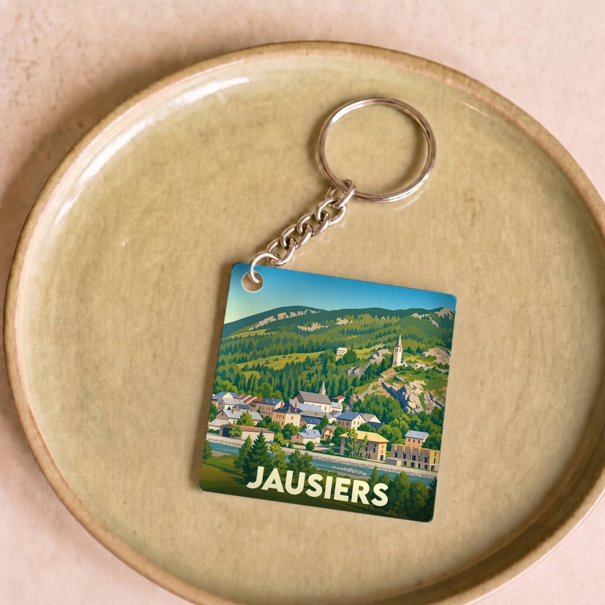 Porte-clés souvenir de la ville de Jausiers avec une illustration stylisée de son paysage montagneux.