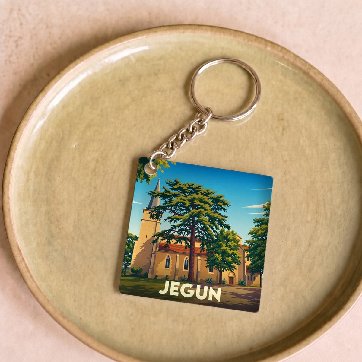 Porte-clés souvenir de la ville de Jegun avec une illustration stylisée de son église.