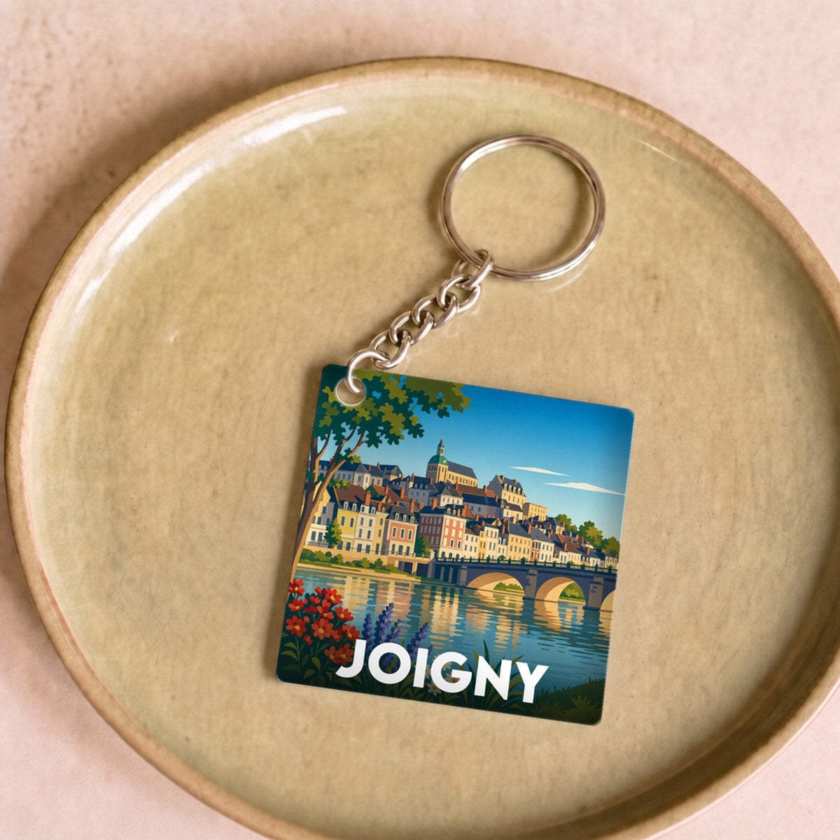 Porte-clés souvenir de la ville de Joigny avec une illustration stylisée d'un paysage fluvial.