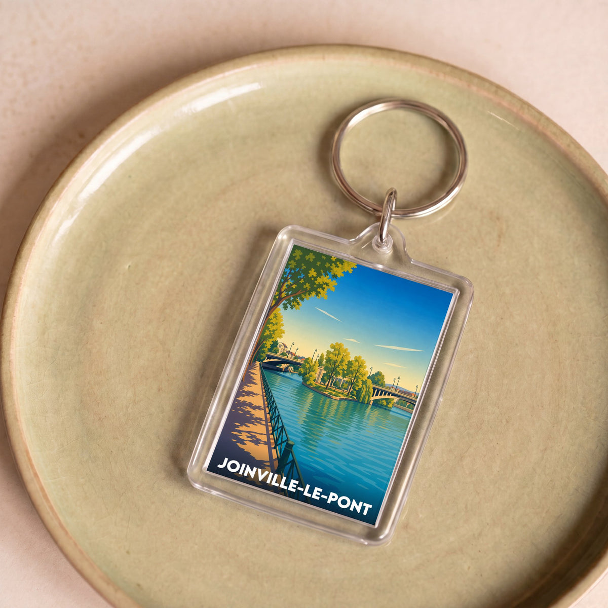 Porte-clés souvenir de la ville de Joinville-le-Pont avec une illustration stylisée d'un pont au bord de l'eau.