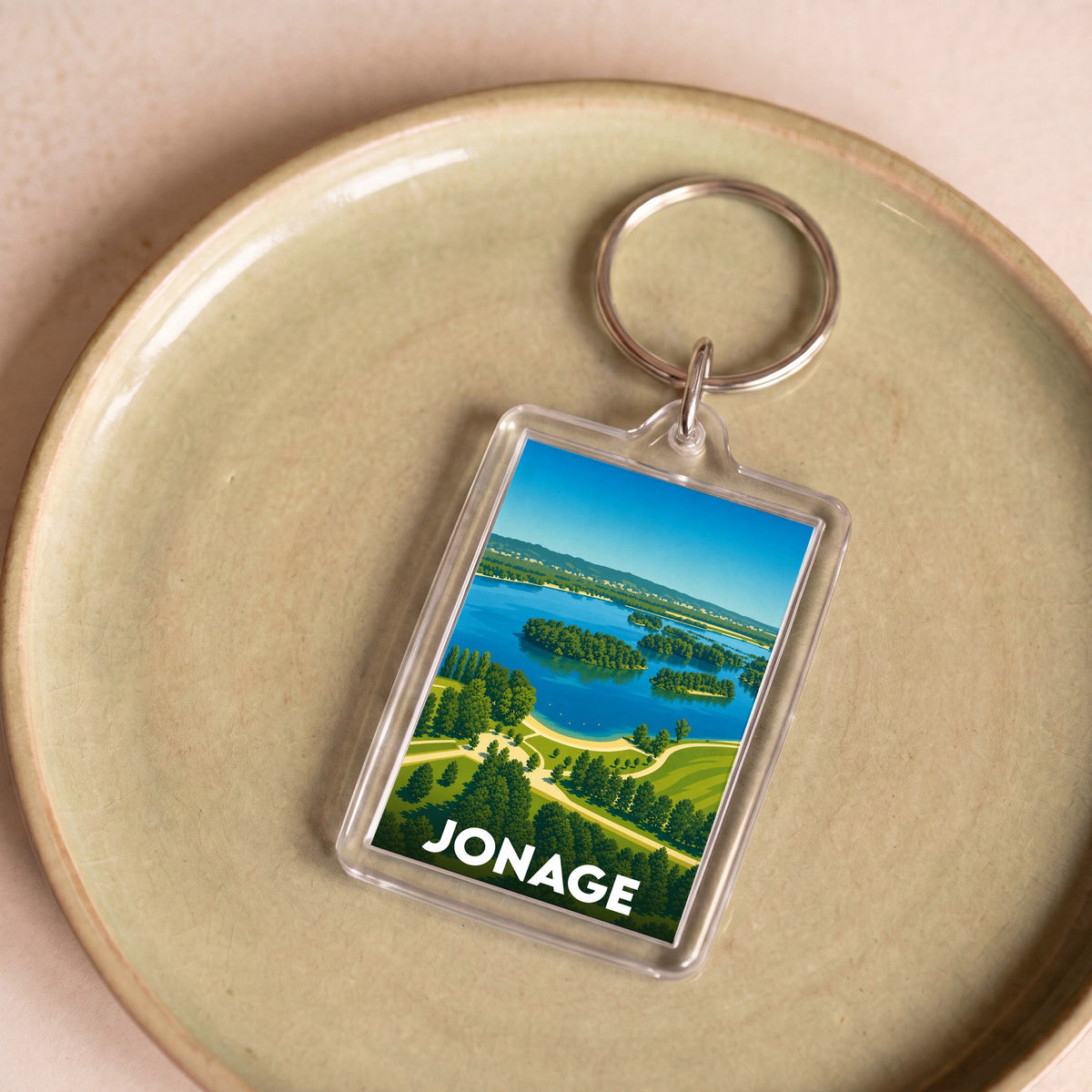 Porte-clés souvenir de la ville de Jonage illustré d'un paysage de lac et de verdure.
