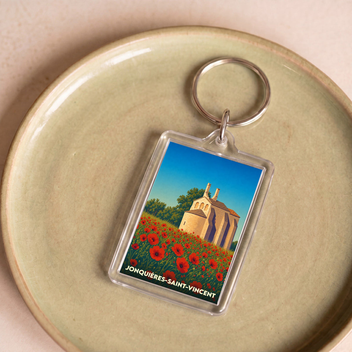 Porte-clés souvenir de la ville de Jonquières-Saint-Vincent avec une illustration stylisée de chapelle et de coquelicots.