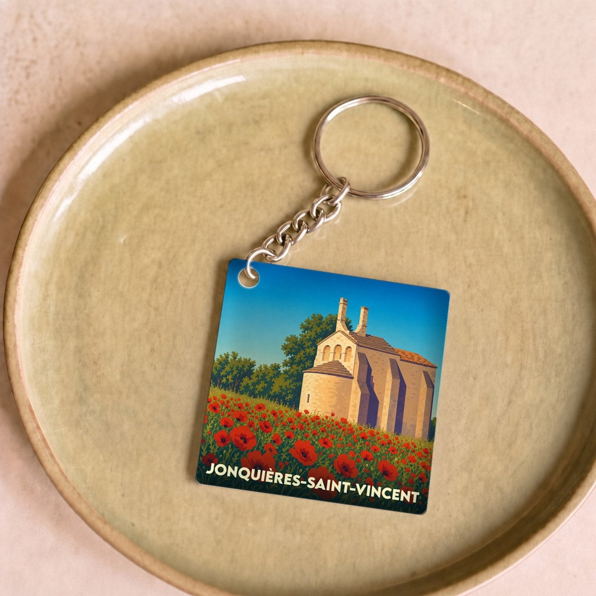 Porte-clés souvenir de la ville de Jonquières-Saint-Vincent avec une illustration stylisée d'une chapelle et de coquelicots.