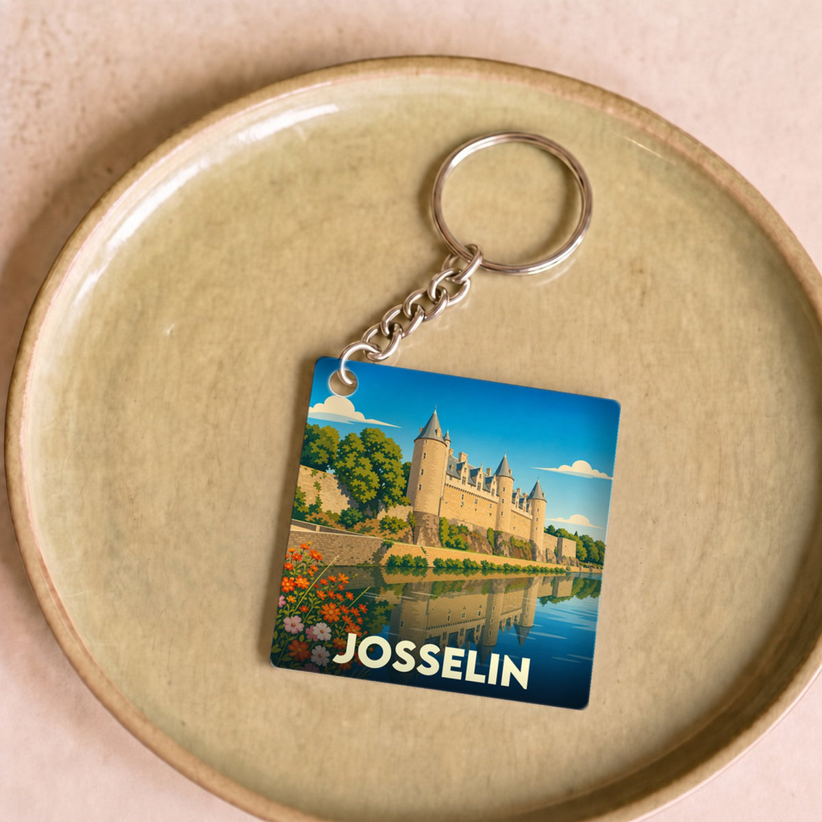 Porte-clés souvenir de la ville de Josselin illustrant son château et ses reflets sur l'eau.