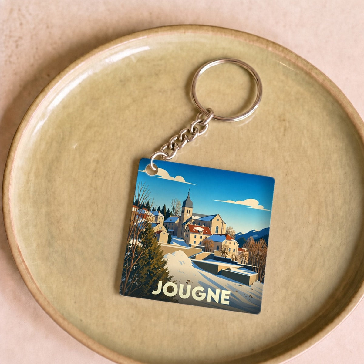 Porte-clés souvenir de la ville de Jougne avec une illustration hivernale stylisée.