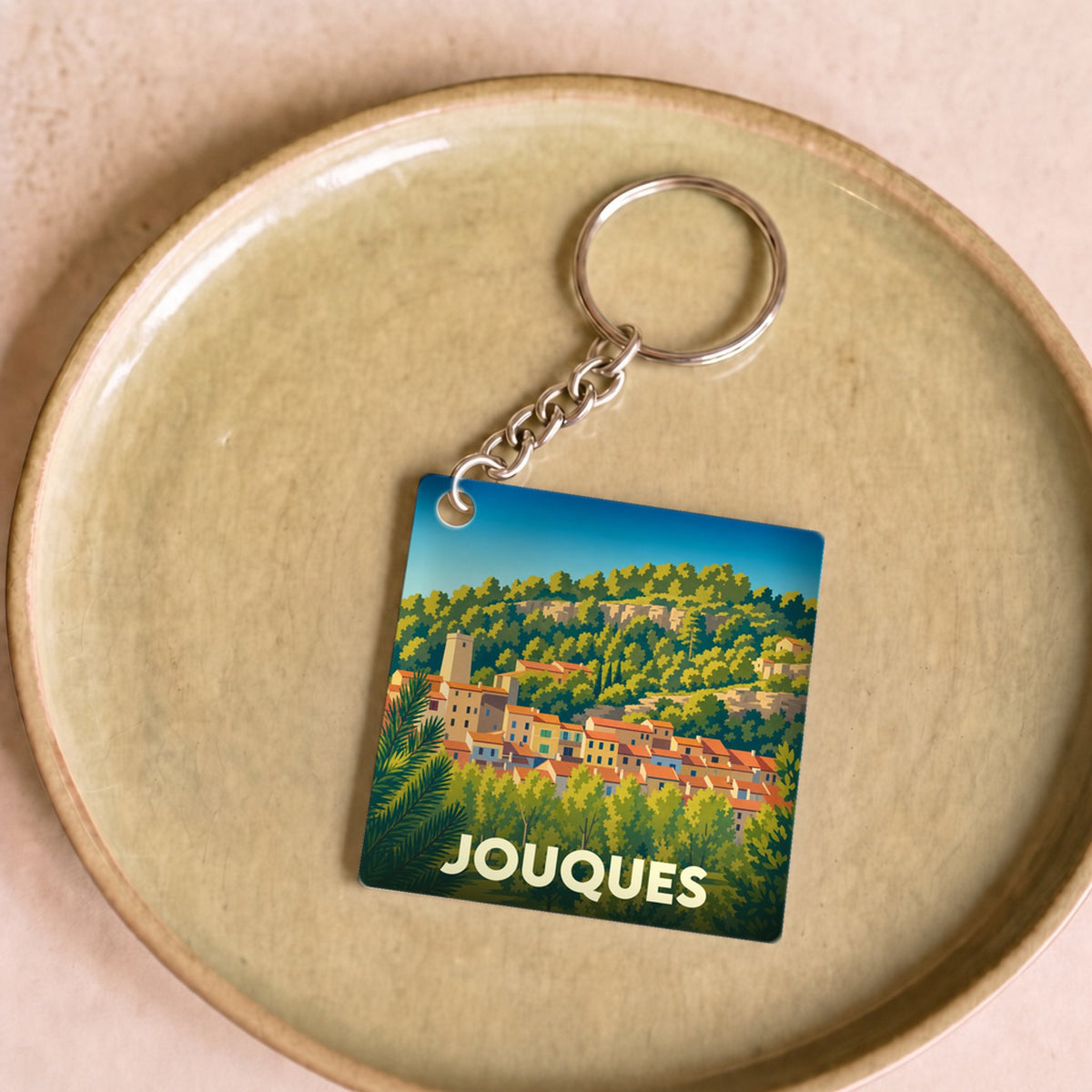 Porte-clés souvenir de la ville de Jouques avec une illustration stylisée.