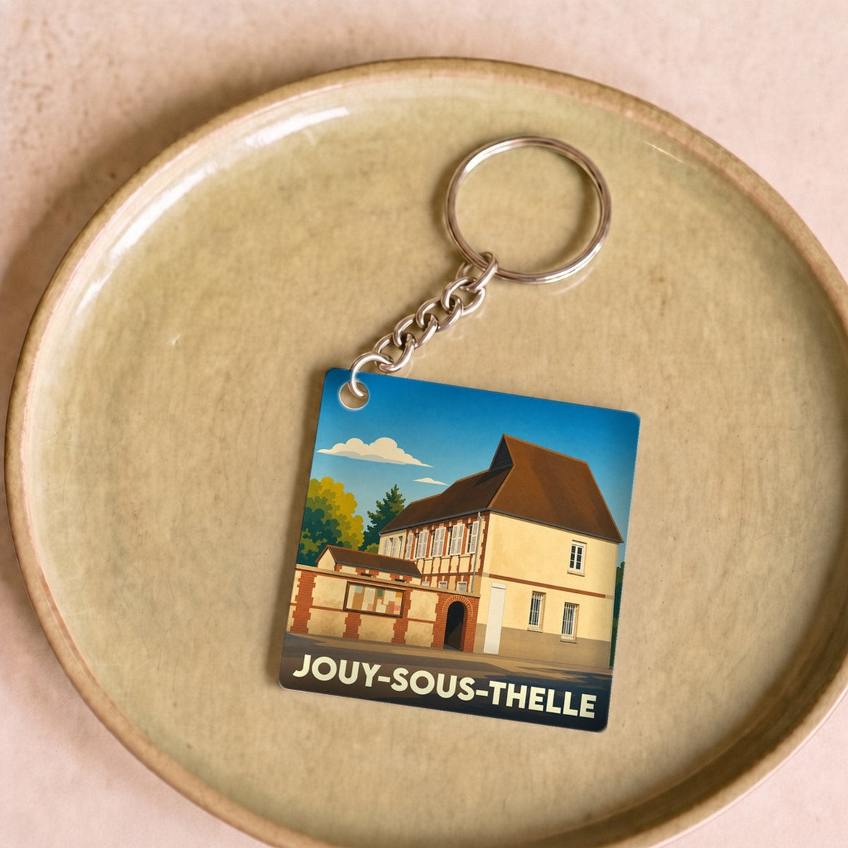 Porte-clés souvenir de la ville de Jouy-sous-Thelle avec une illustration stylisée d'un bâtiment historique.