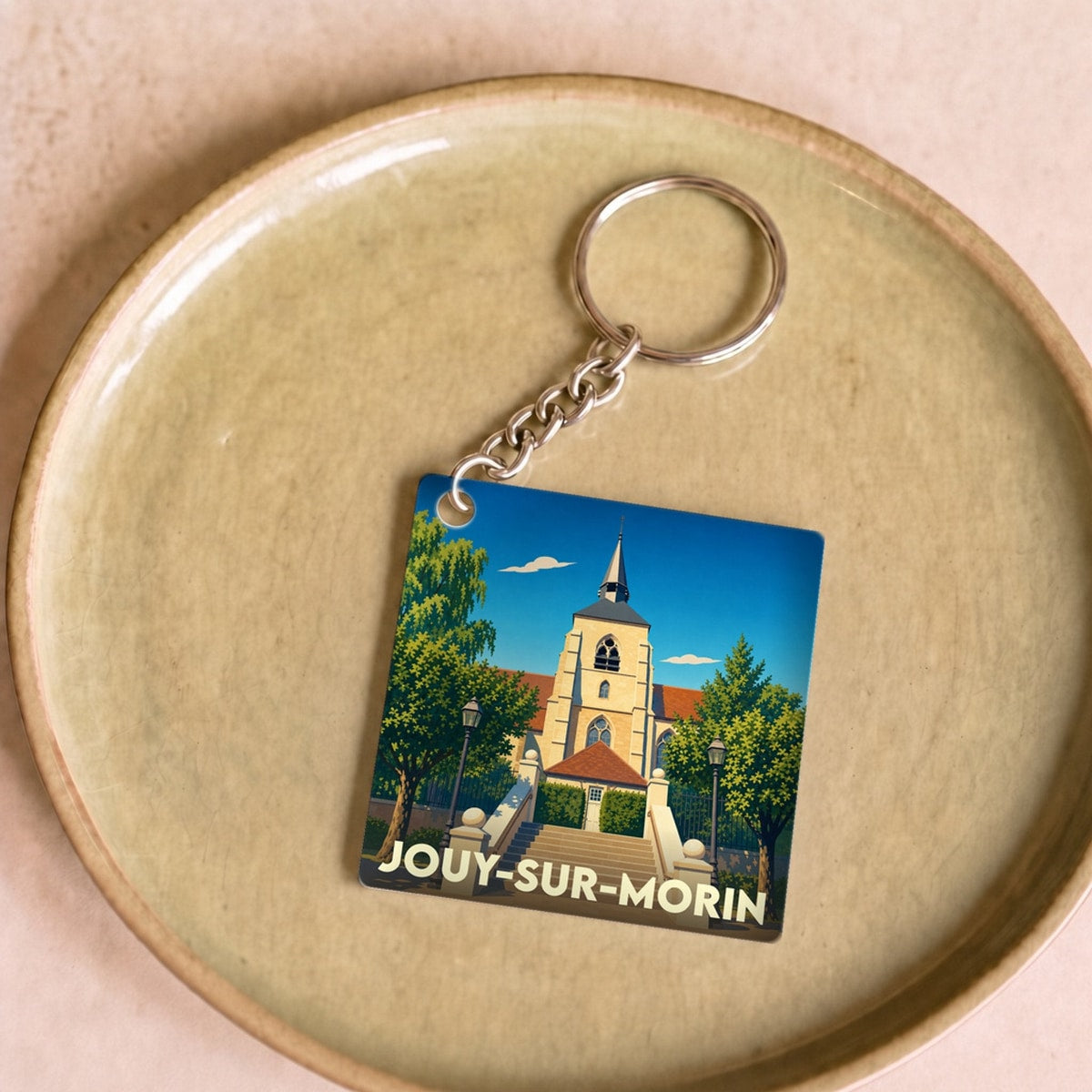 Porte-clés souvenir de la ville de Jouy-sur-Morin avec une illustration stylisée de son église.