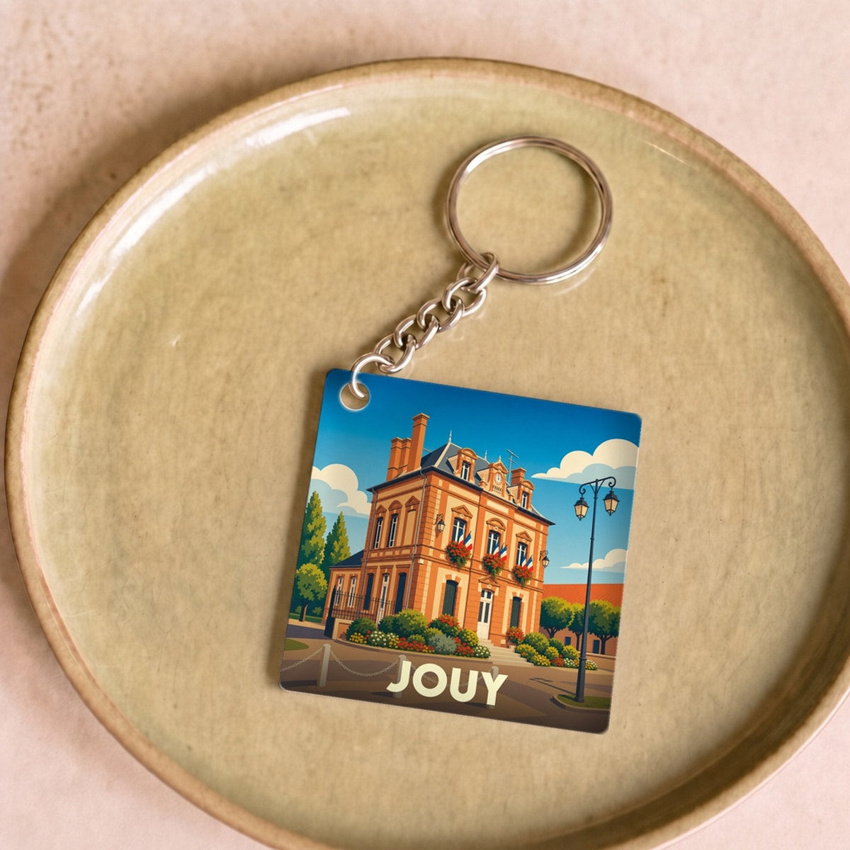Porte-clés souvenir de la ville de Jouy avec une illustration stylisée de son hôtel de ville.