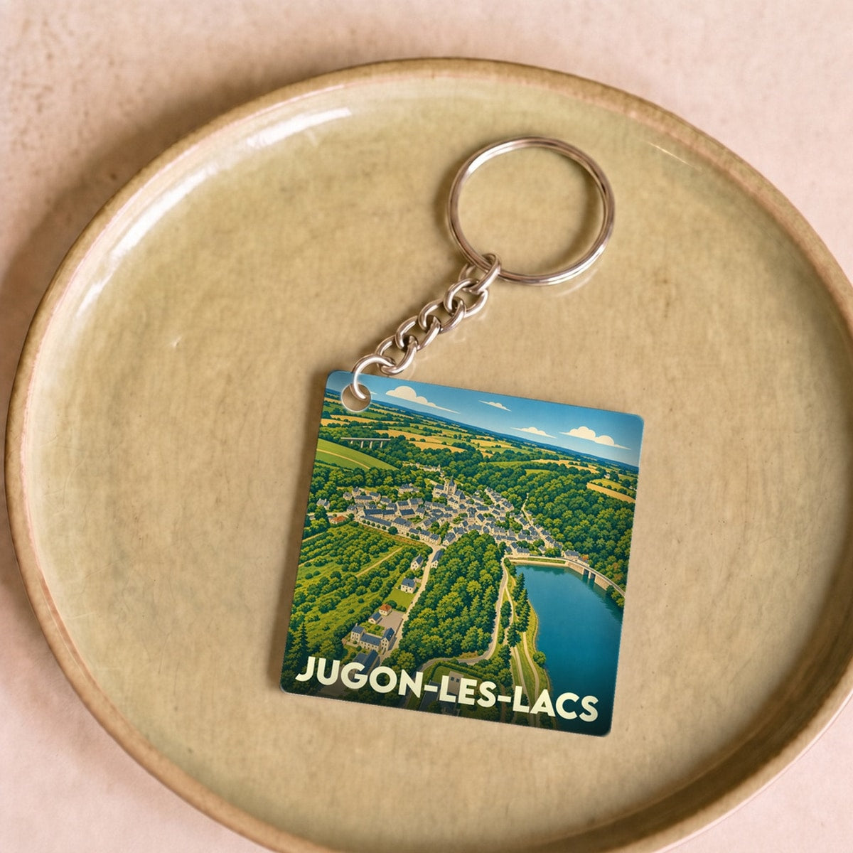 Porte-clés souvenir de la ville de Jugon-les-Lacs avec une illustration stylisée.