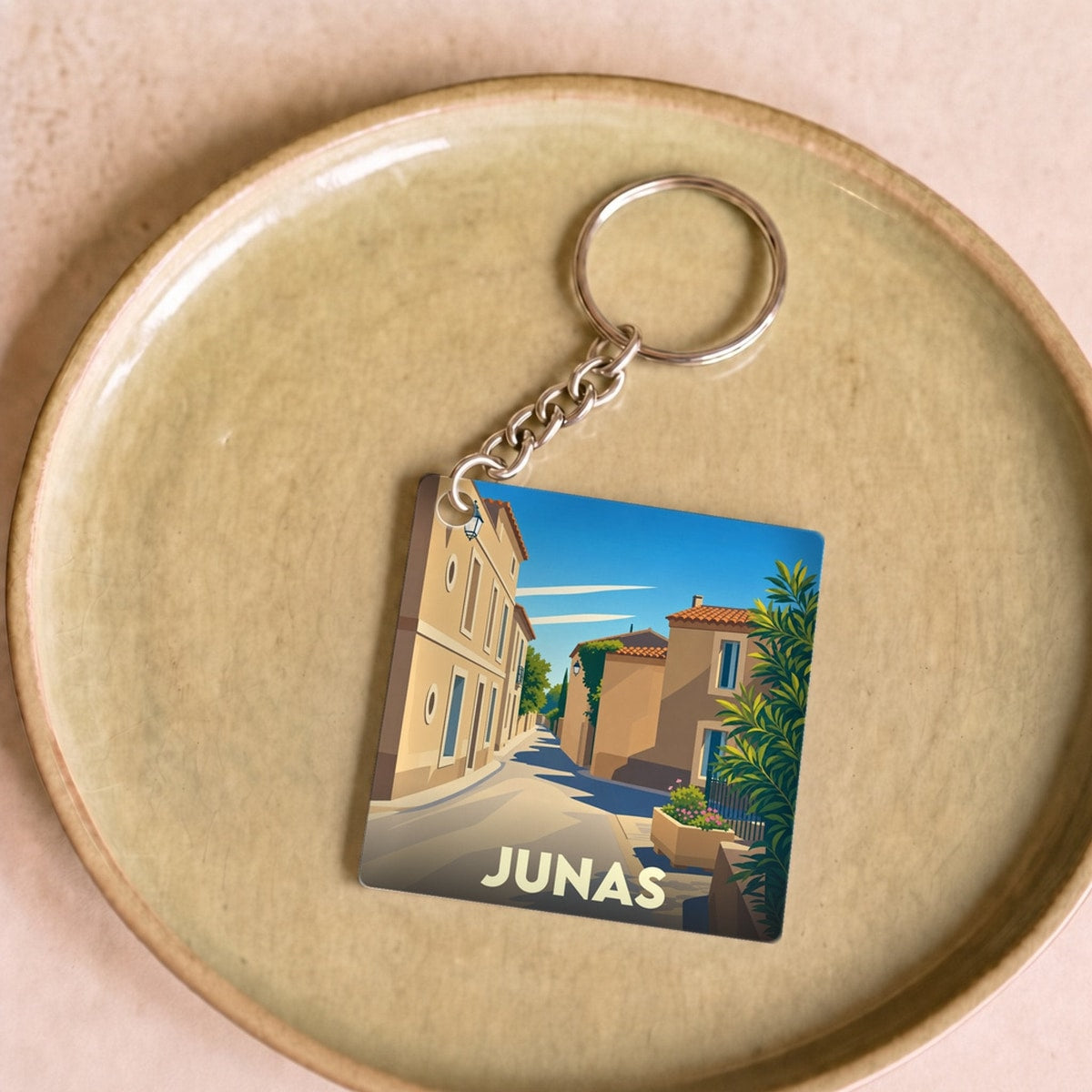 Porte-clés souvenir de la ville de Junas avec une illustration stylisée d'une ruelle ensoleillée.