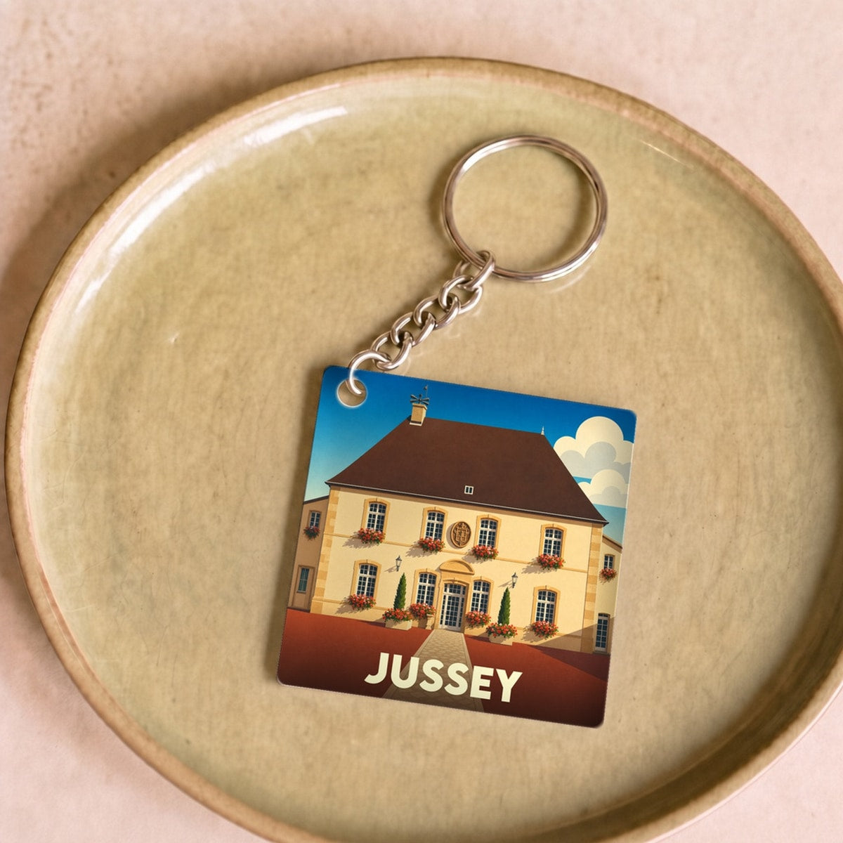 Porte-clés souvenir de la ville de Jussey avec une illustration stylisée de son hôtel de ville.