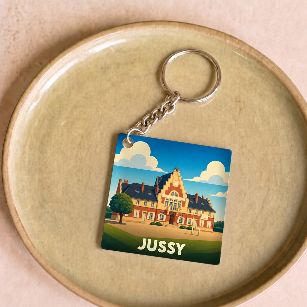 Porte-clés souvenir de la ville de Jussy avec une illustration stylisée.