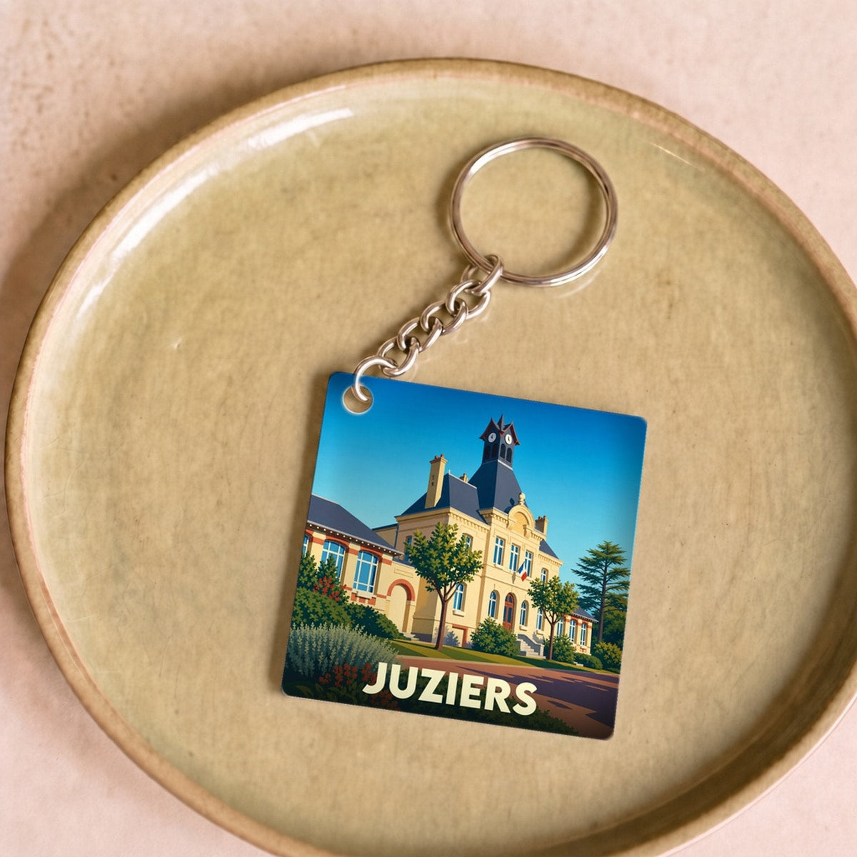 Porte-clés souvenir de la ville de Juziers avec une illustration stylisée de son hôtel de ville.