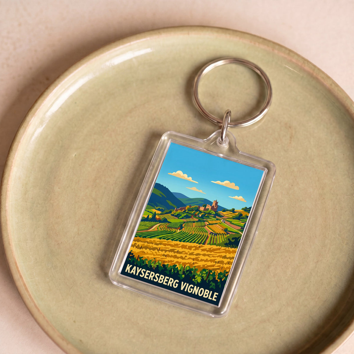 Porte-clés souvenir de la ville de Kaysersberg Vignoble avec une illustration stylisée de son paysage.