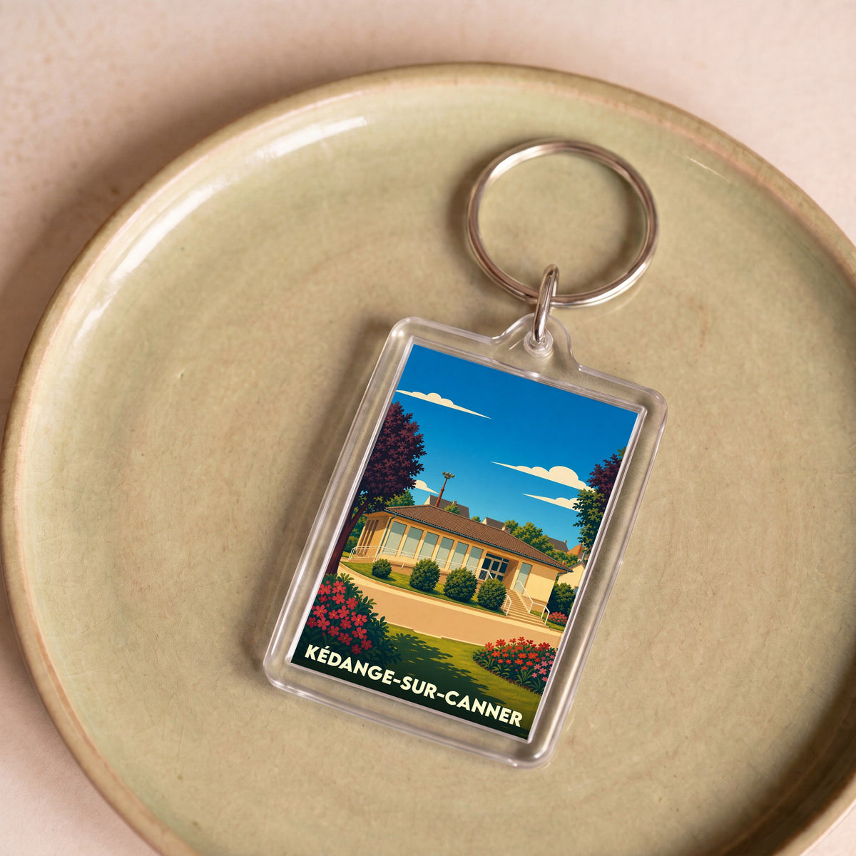 Porte-clés souvenir de la ville de Kédange-sur-Canner avec une illustration stylisée d'un bâtiment local.