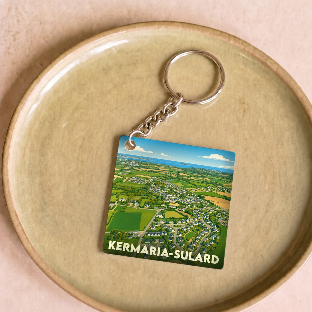 Porte-clés souvenir de la commune de Kermaria-Sulard avec une illustration stylisée vue du ciel.