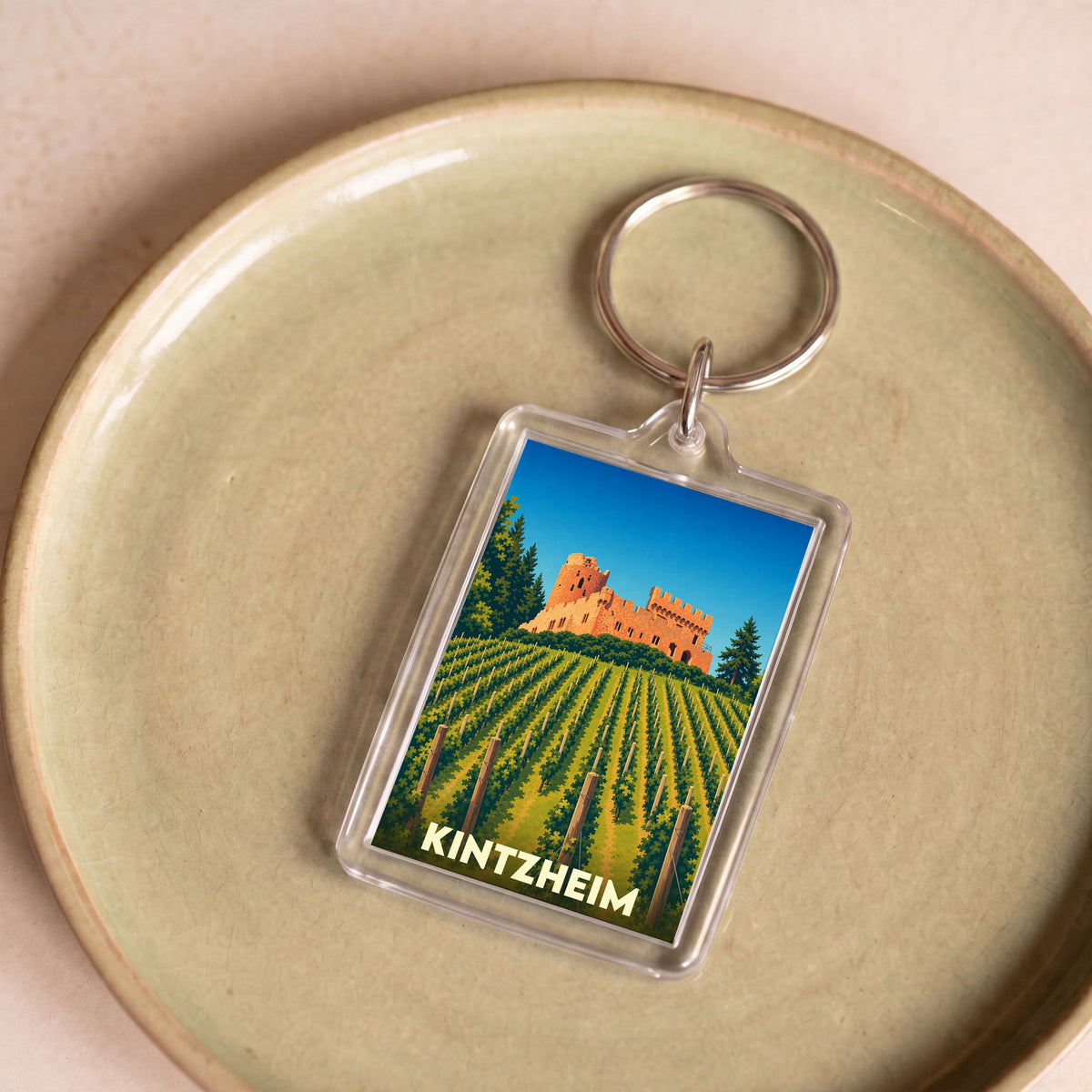 Porte-clés souvenir de la ville de Kintzheim avec une illustration stylisée d'un château dominant un vignoble.