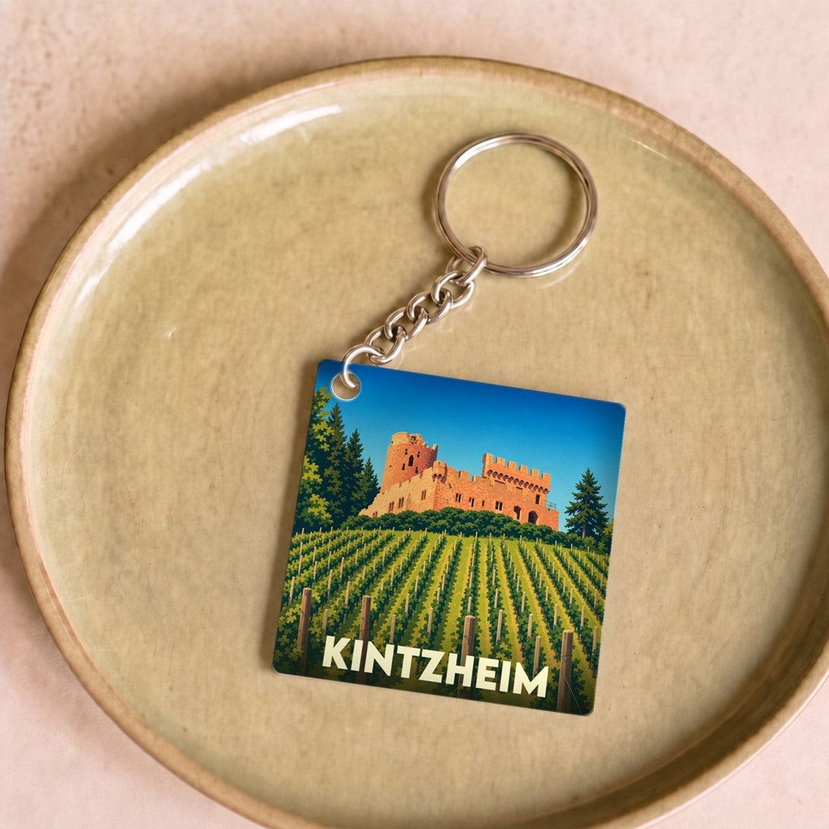 Porte-clés souvenir de la ville de Kintzheim avec une illustration stylisée d'un château dominant un vignoble.