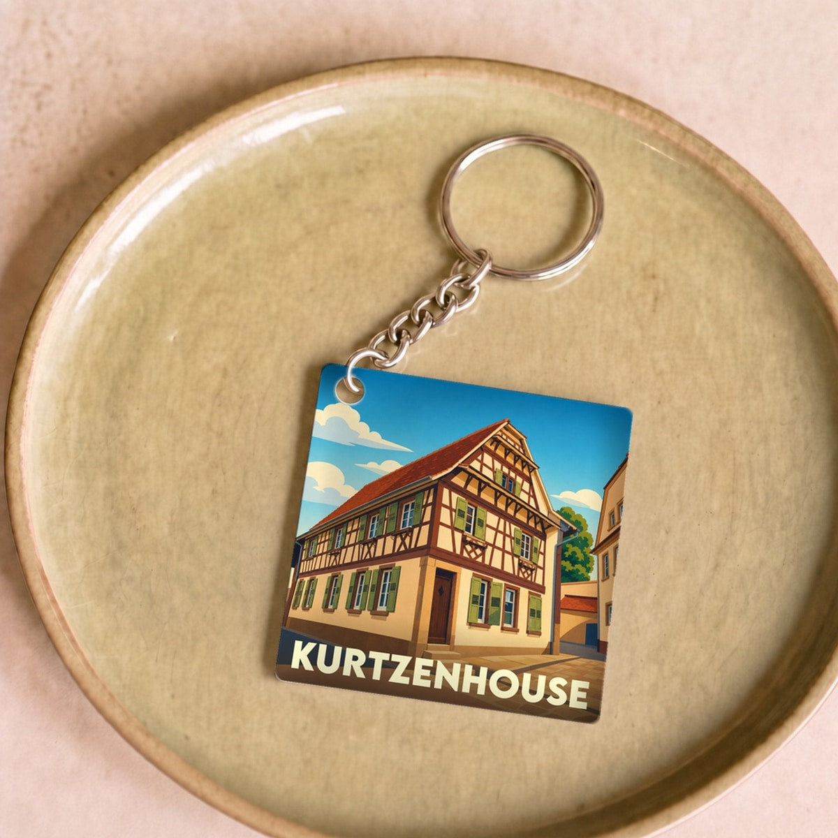 Porte-clés souvenir de la ville de Kurtzenhouse avec une illustration stylisée d'une maison à colombages.