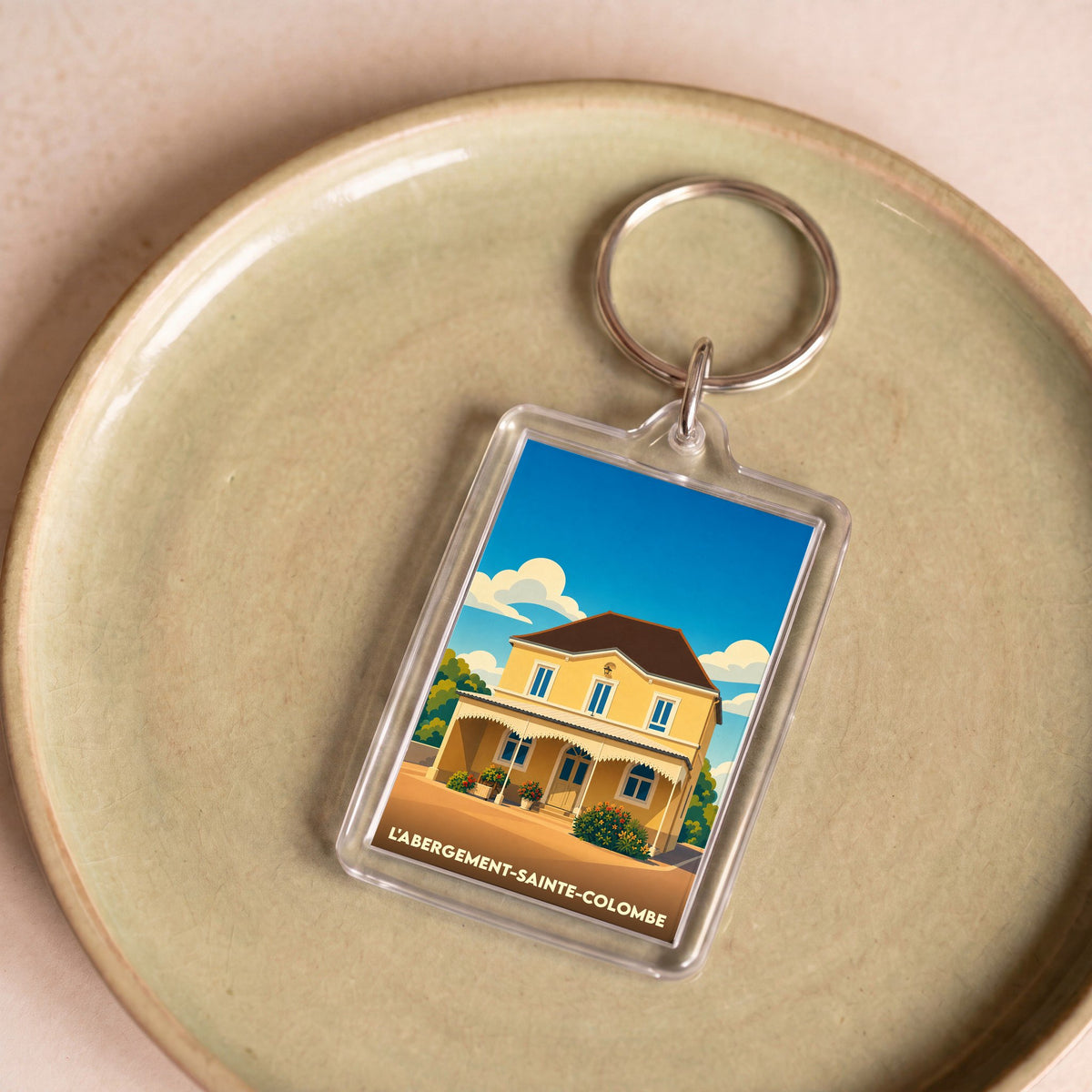Porte-clés souvenir de la ville de L'Abergement-Sainte-Colombe avec une illustration stylisée d'une maison jaune.