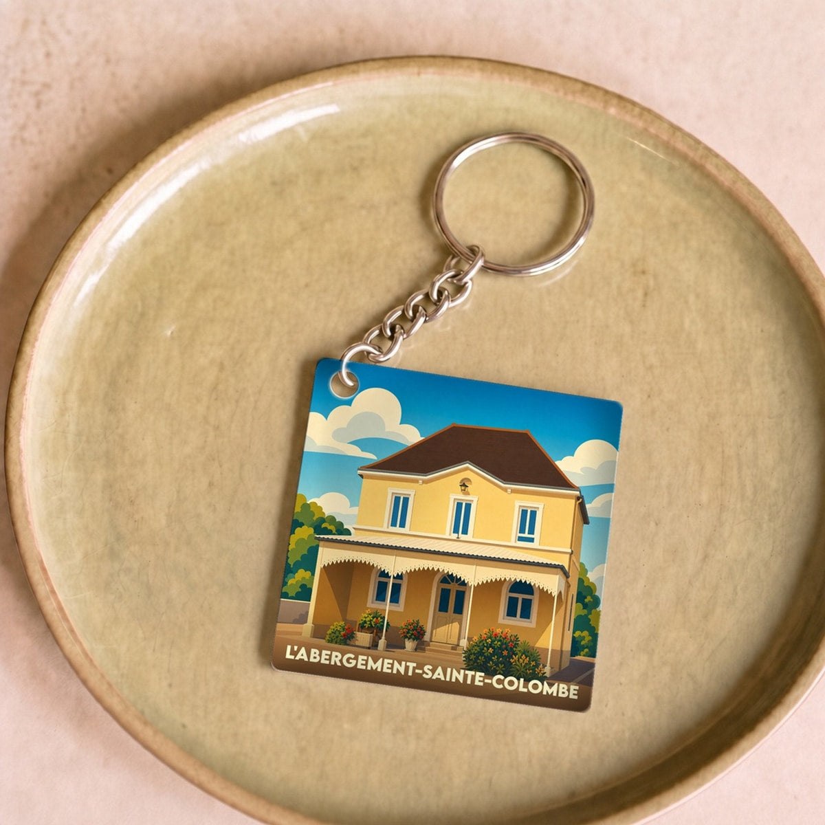 Porte-clés souvenir de la ville de L'Abergement-Sainte-Colombe avec une illustration stylisée d'une maison jaune.